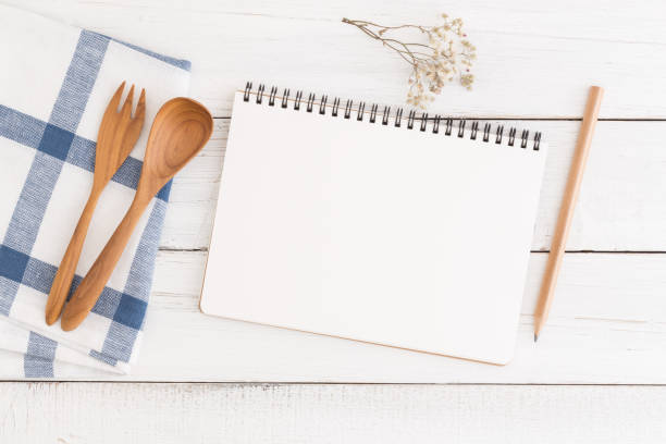 istock Flat lay photo of cooking desk with notebook and spoon,Empty open notebook on white wooden table, top view 917174090