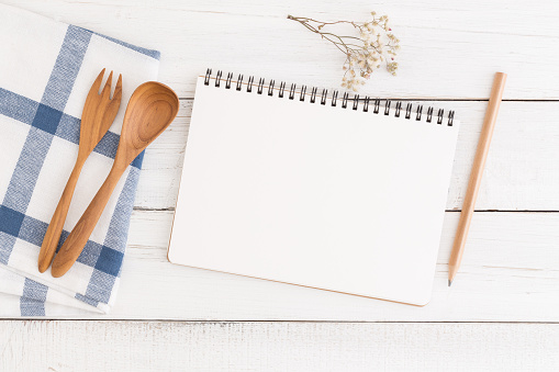 Flat lay photo of cooking desk with notebook and spoon,Empty open notebook on white wooden table, top view