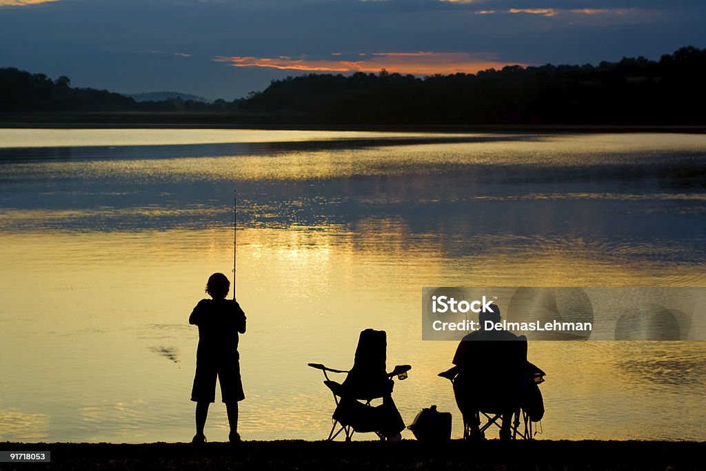 A silhouette of two people fishing at sunrise Fishing at a Berks County,Pennsylvania lake. Fishing Stock Photo