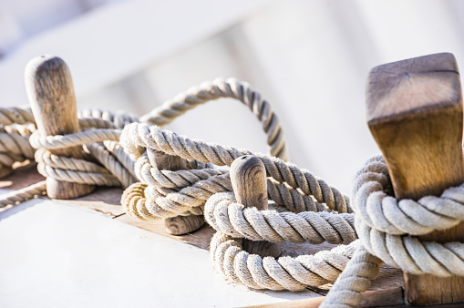 Close-up of moored ropes on wooden cleats on old sailing boat