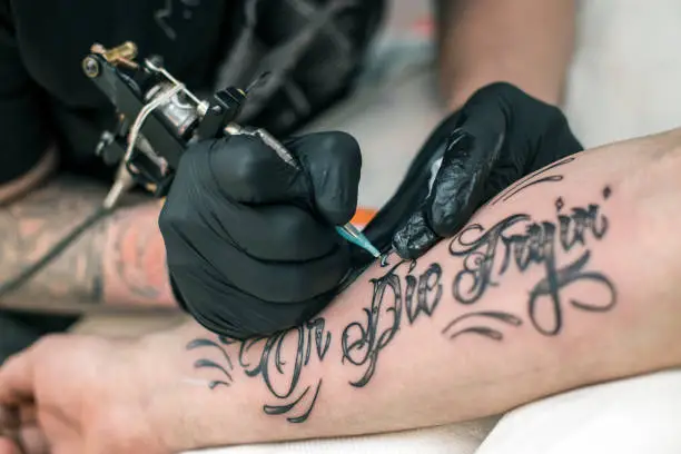 Tattoo artist tattooing a male model. Unrecognizable Caucasian man.