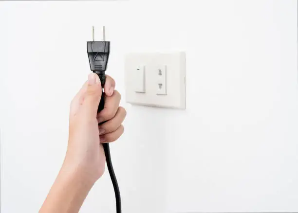 Photo of Plug on hand or unplug and outlet on white wall background , electric shock