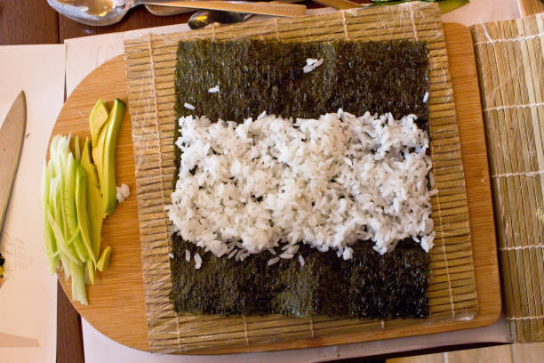 istock Nori algae leaf with rice for rolls with cucumber and avocado on wooden board 917203860