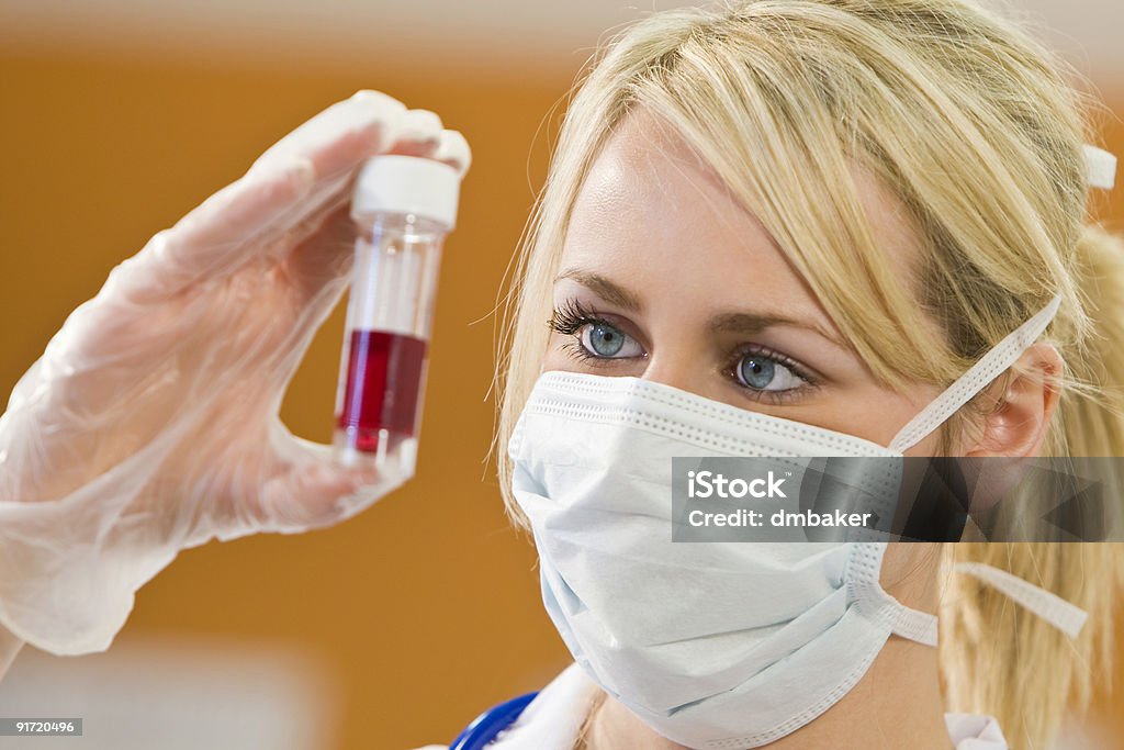 Woman Doctir or Nurse Analyzing Blood Sample A young female doctor/nurse looking at a blood sample  Adult Stock Photo