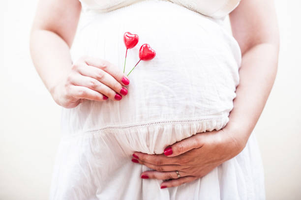Pregnant Woman Holding Two Red Hearts in Her Hand stock photo
