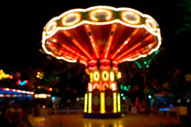 neon lights on chain carousel in amusement park, night blurred shot