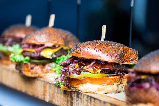 свежее пламя жареные гамбургеры отображается в ряд на продовольственном рынке - street food фотографии стоковые фото и изображения