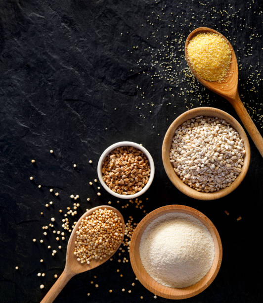 istock Various groats, cereals. Different types of groats in bowls and on a spoons on a  black background, top view 917213920