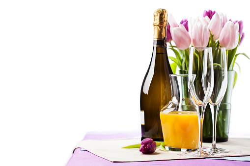 Two empty champagne flutes and a bottle of sparkling wine with tulips on background