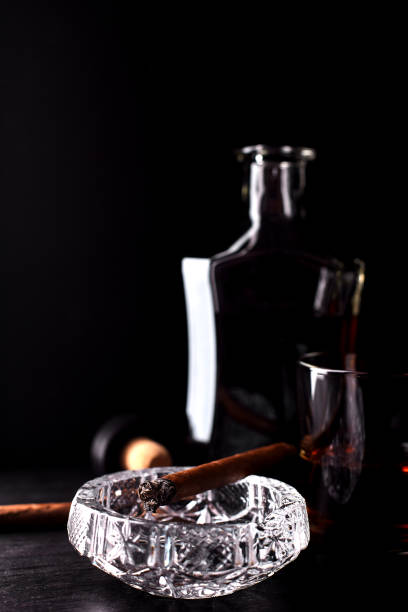 Glass of whiskey with smoking cigar.