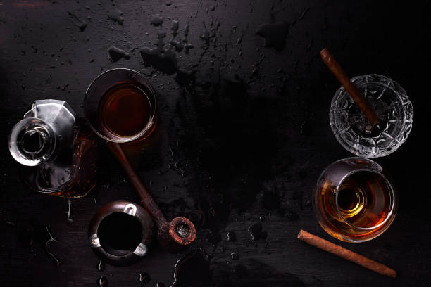 Glass of whiskey with smoking cigar.