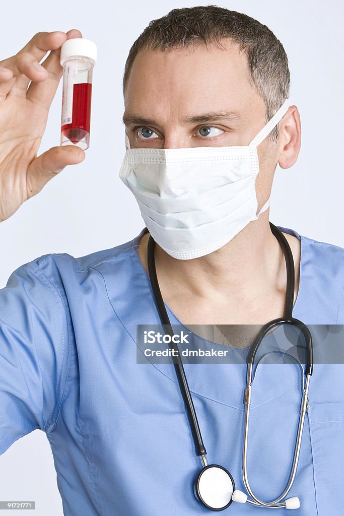 Врач с Хирургическая маска глядя на образцы крови - Стоковые фото Болезнь роялти-фри