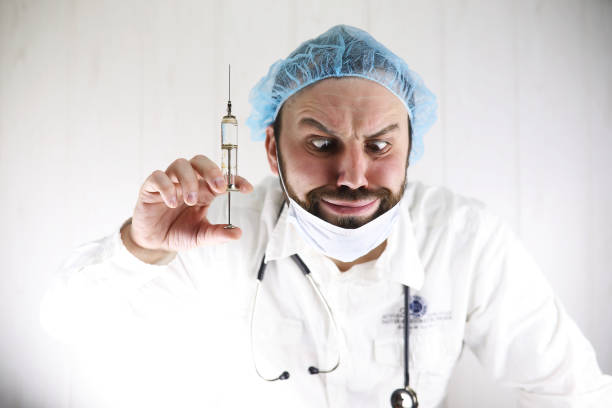 istock Crazy bearded doctor in a white coat and old syringe 917224144