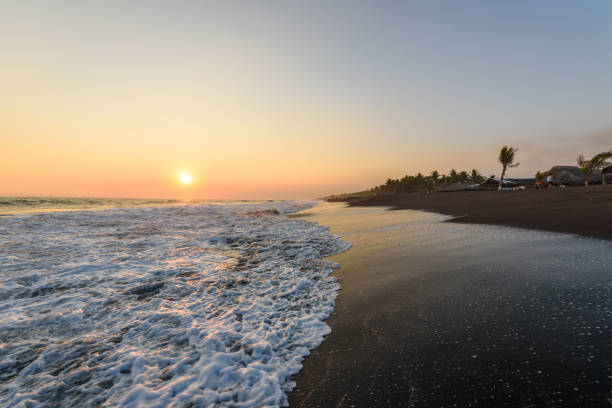Sunset at Beach with Black Sand in Monterrico, Guatemala. Known for its volcanic black sand beaches and annual influx of sea turtles. Travel destination of Guatemala. Monterrico is situated on the Pacific coast in the department of Santa Rosa. Travel destination in Europe. puesta de sol en la playa con arena negra de monterrico, guatemala. conocida por sus playas de arena negra volcánicas y una afluencia anual de tortugas marinas. destinos de guatemala. monterrico está situado en la costa del pacífico en el departamento de santa rosa.