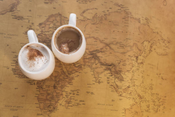 istock Two white cups of coffee stand on a world map against a light background 917227702