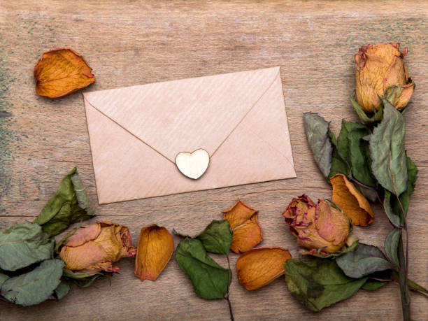 istock Dried orange roses and envelope on wooden background, copy space 917228156
