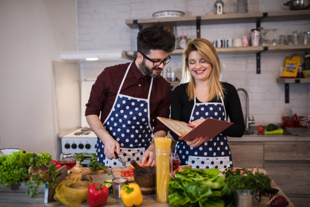 Young couple look at a recipe book in the kitchen.