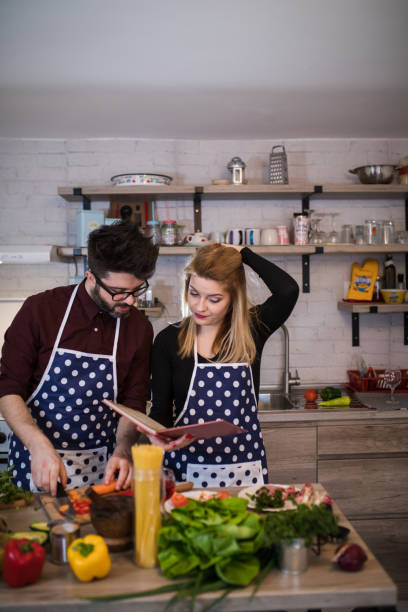 istock Young couple look at a recipe book in the kitchen. 917229802