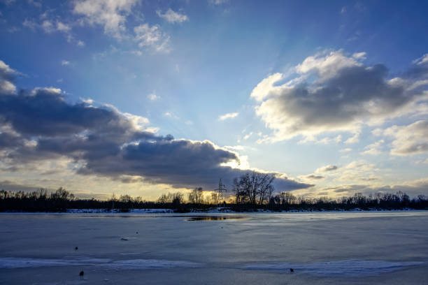 colorful winter sunset on frozen river ice with dramatic clouds