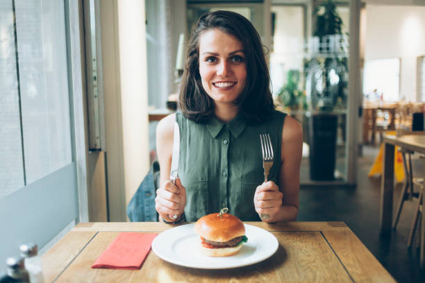 Elegant woman eating burger in restaurant