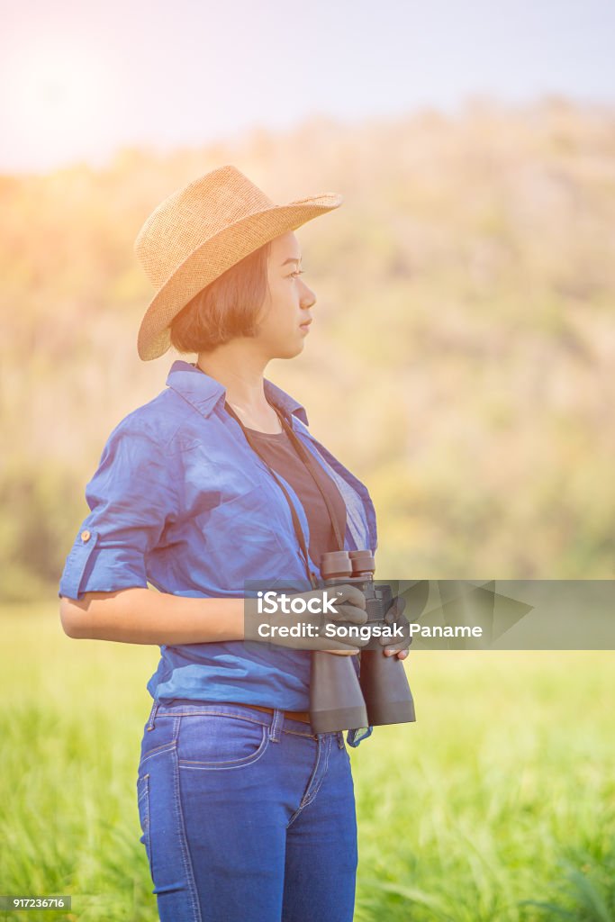 young teenager wear hat and hold binocular in grass field Young asian teenagershort hair wear hat and hold binocular in grass field countryside Thailand 14-15 Years Stock Photo