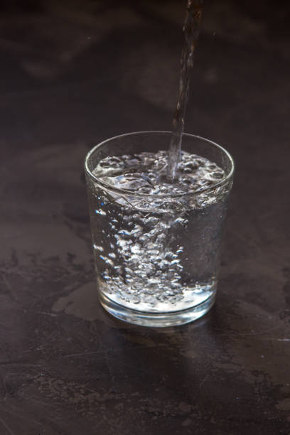 istock Water pouring into a glass, dark background 917236892
