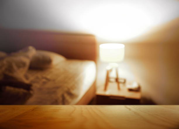 parte superiore del tavolo in legno con camera da letto notturna sfocata con sfondo interno della casa lampada - comodino foto e immagini stock
