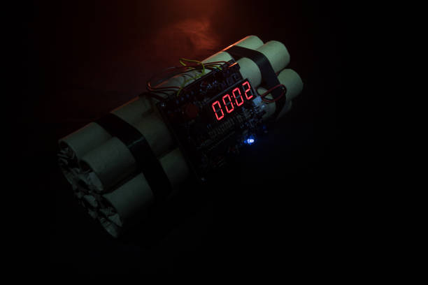 istock Image of a time bomb against dark background. Timer counting down to detonation illuminated in a shaft light shining through the darkness 917239566
