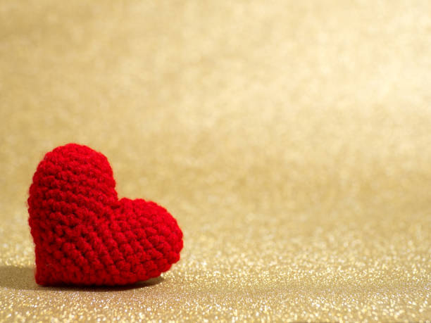 istock Handmade red yarn heart on gold abstract background. Copy space for text, Valentines day, love concept and love background 917245334