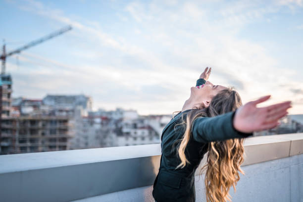 Businesswoman celebrating on urban rooftop stock photo