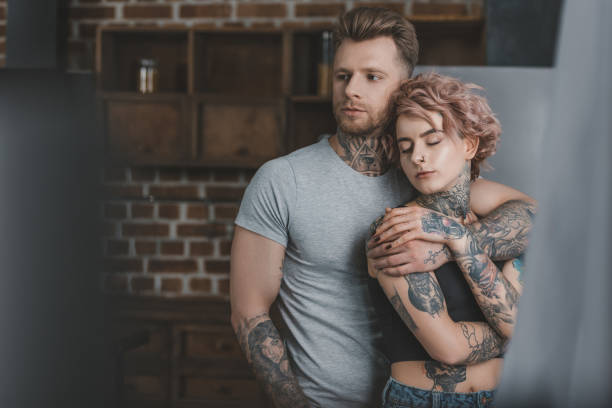 istock tender tattooed couple hugging in kitchen 917250744