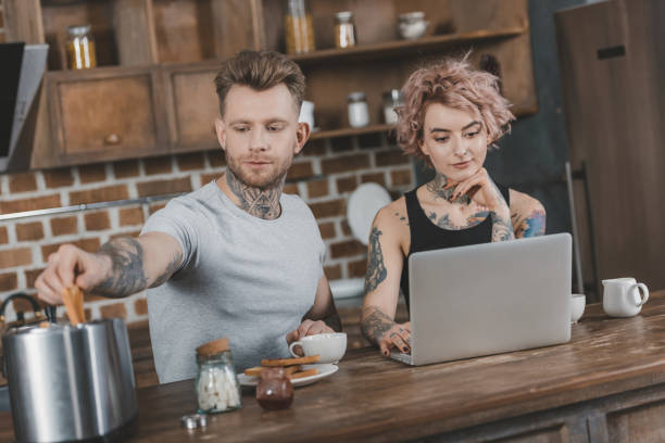 istock young tattooed couple using laptop during breakfast in kitchen 917250948
