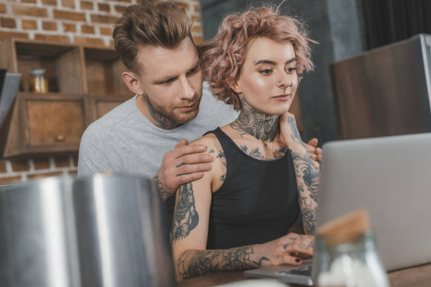istock tattooed couple using laptop at home 917251170