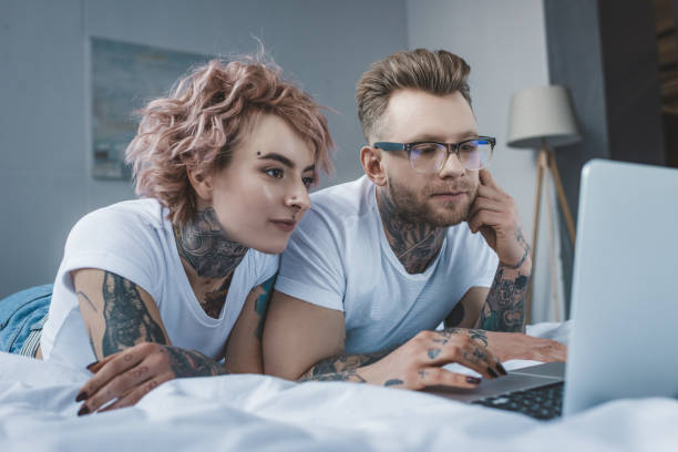 istock young tattooed couple using laptop on bed in bedroom 917251282