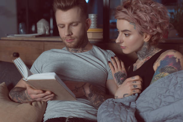 istock tattooed couple resting and reading book at home 917251658
