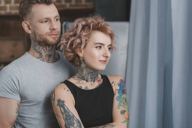 istock young tattooed couple hugging and looking away 917251892