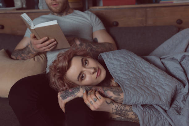 istock tattooed couple relaxing and reading book at home 917252398