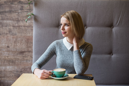 woman drinking coffee in the morning at restaurant (soft focus on the eyes)