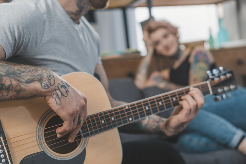Tattooed Boyfriend Playing On Acoustic Guitar For His Girlfriend At Home  Stock Photo - Download Image Now - iStock