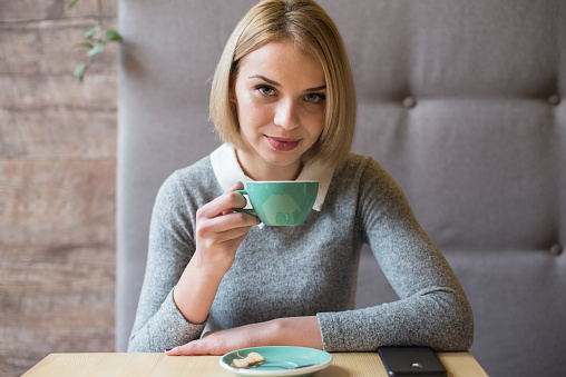 woman drinking coffee in the morning at restaurant (soft focus on the eyes)