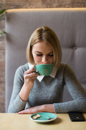 woman drinking coffee in the morning at restaurant (soft focus on the eyes)