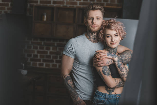 istock young tattooed couple hugging and looking at camera 917255414