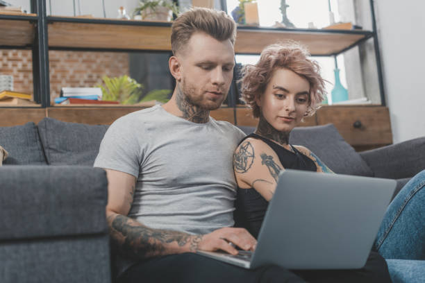 istock attractive tattooed couple using laptop on sofa at home 917255444