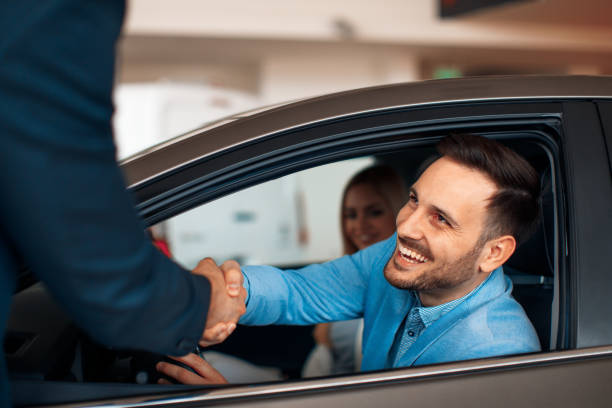 Pareja joven estrechándole la mano después de un exitoso coche comprar - foto de stock