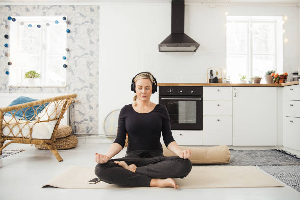 mujer en el hogar en la cocina haciendo yoga y meditación - alternative energy audio fotografías e imágenes de stock