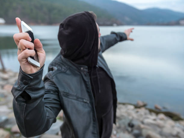 uomo in piedi sulla spiaggia del lago e gettando il suo smartphone in acqua - lanciare foto e immagini stock