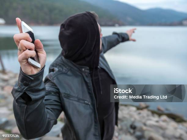 Man Standing On Lakes Beach And Throwing His Smart Phone Into The Water Stock Photo - Download Image Now
