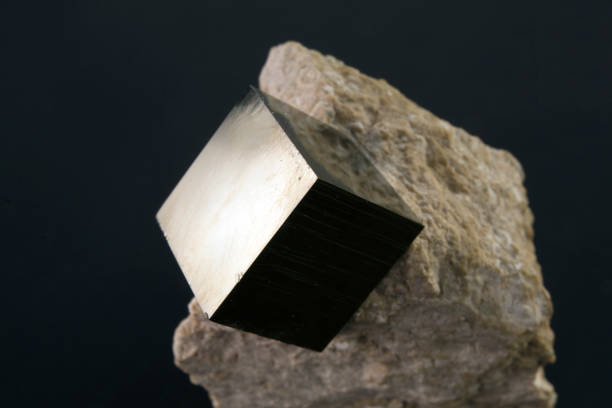 Shiny smooth regular shape pyrite cube on a dark background stock photo