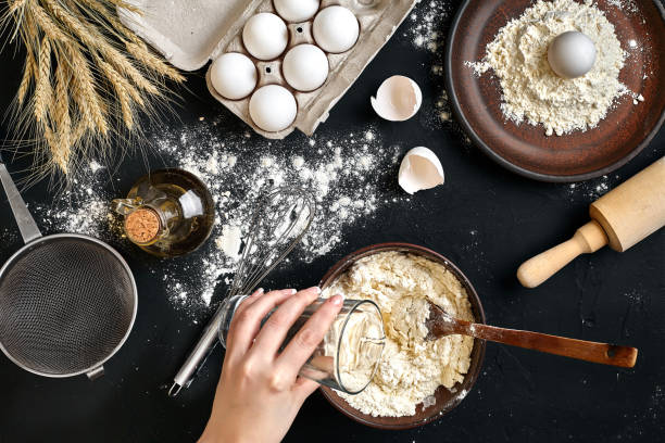 istock Female hands making/ mixing dough in brown bowl on black table, baking preparation close-up 917276572