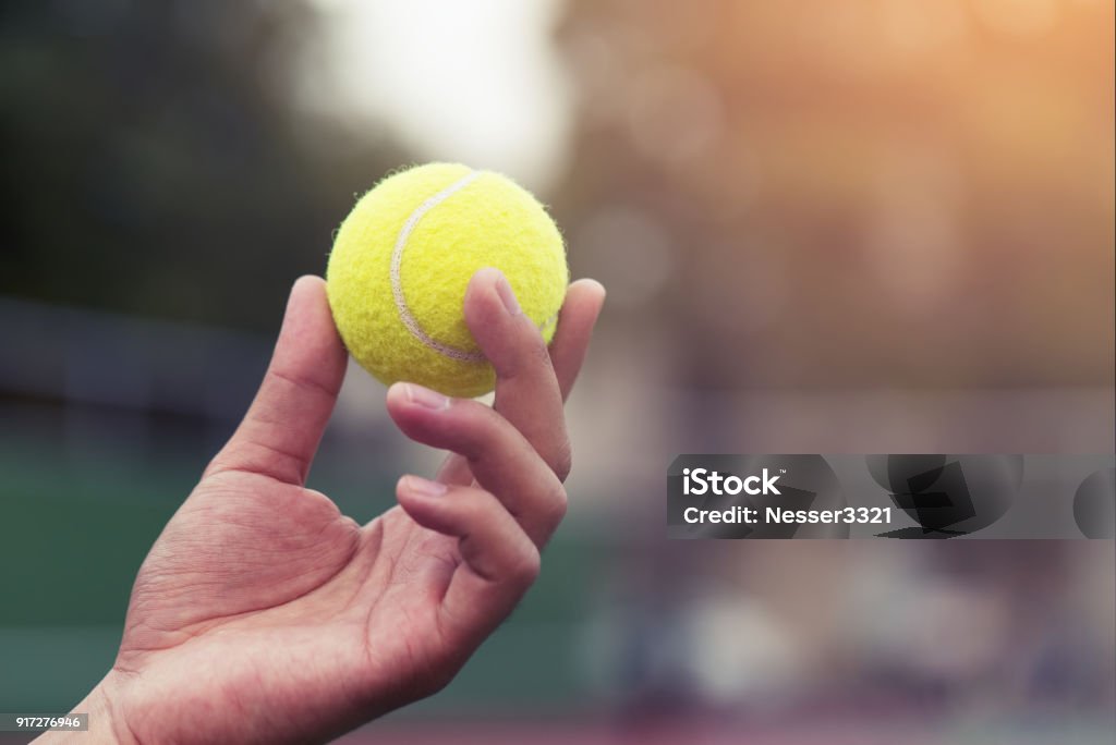 Tennis player holding the ball and getting ready to serve. Tennis Ball Stock Photo